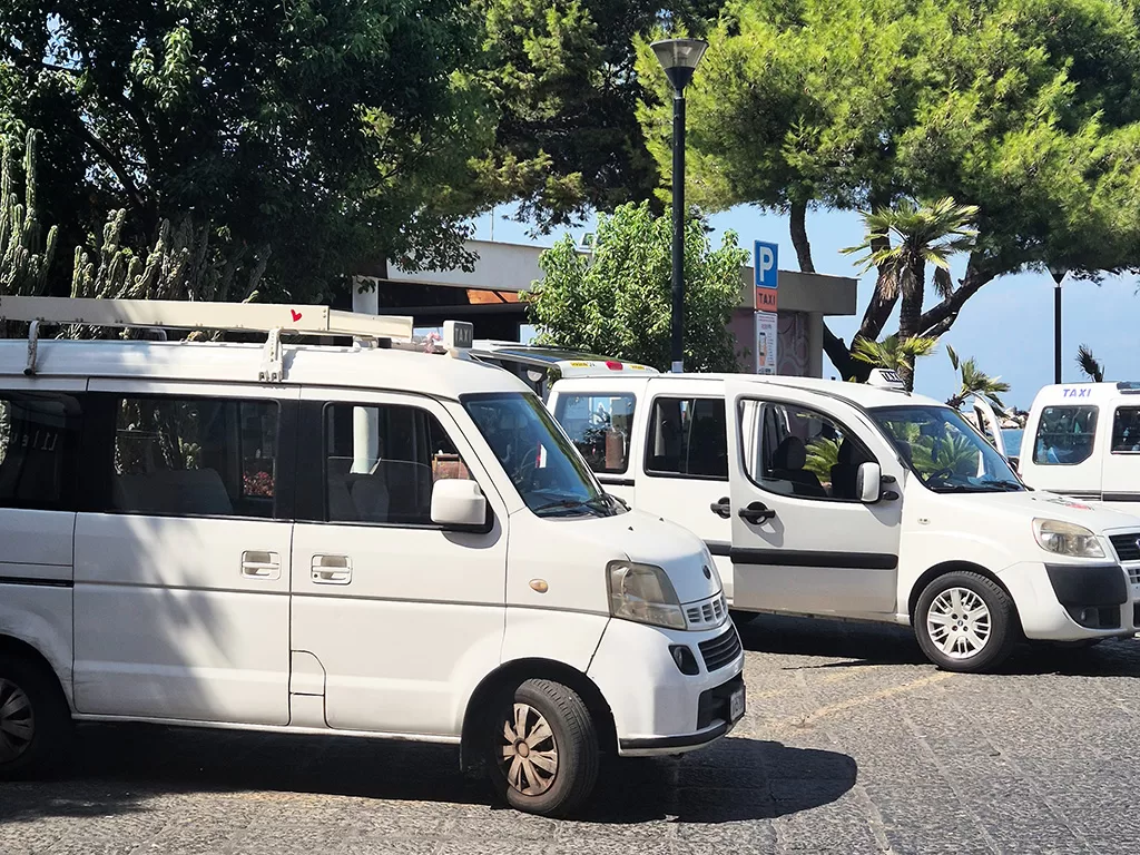 white taxis lined up at procida's marina grande