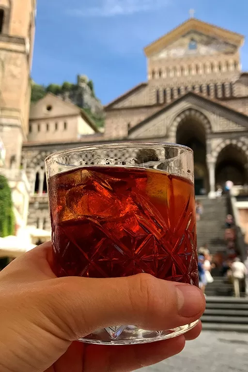 full glass of negroni posed in front of amalfi cathedral