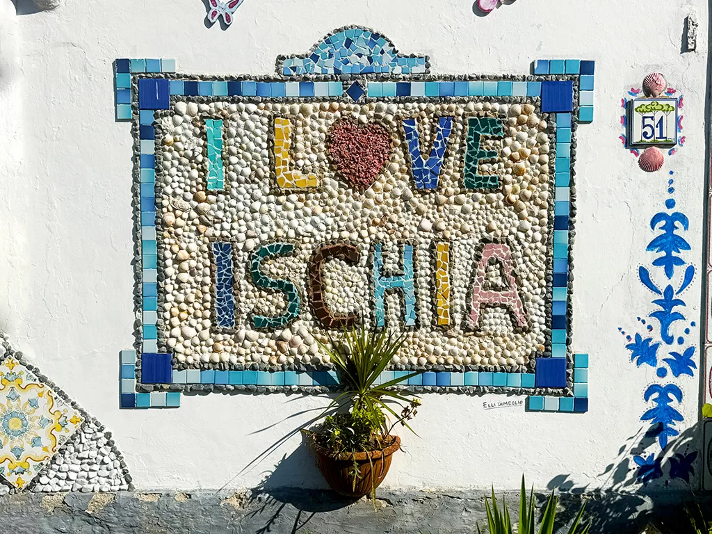 colorful pebble and tile sign built into a wall saying 'i love ischia'
