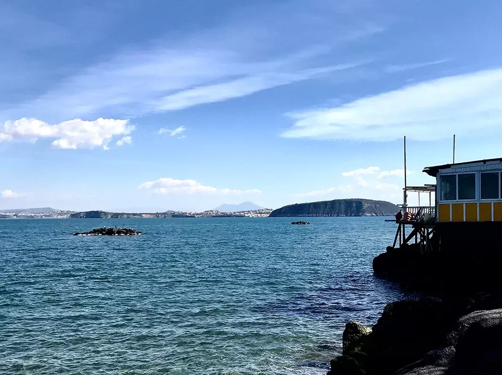 view of procida from ischia with mount vesuvius in the distance