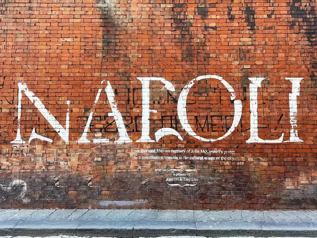 white napoli street art on red brick wall