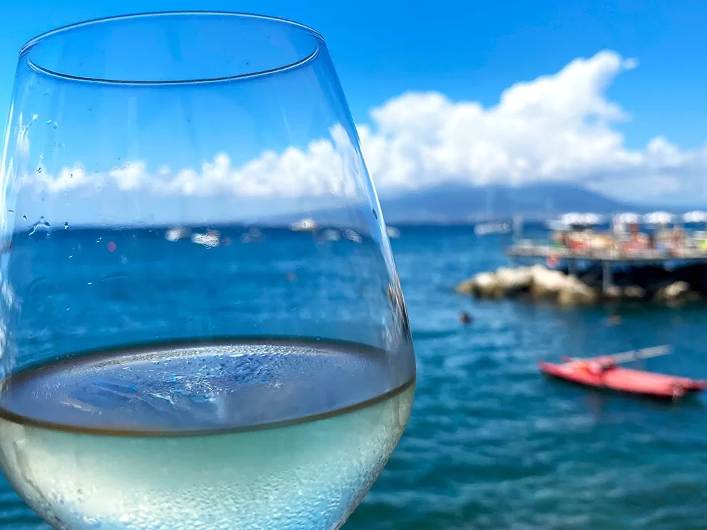 glass of white wine with sea and beach club beyond