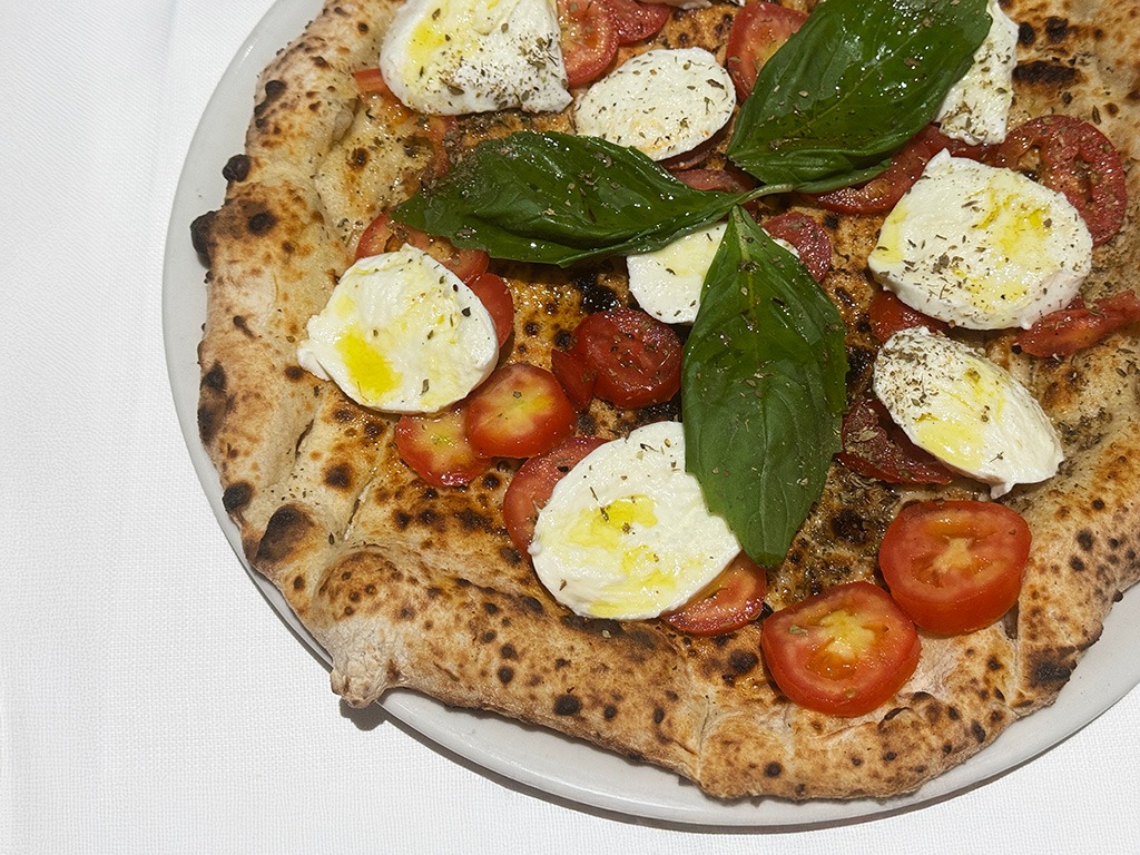 pizza with slices of mozzarella, tomatoes and basil leaves