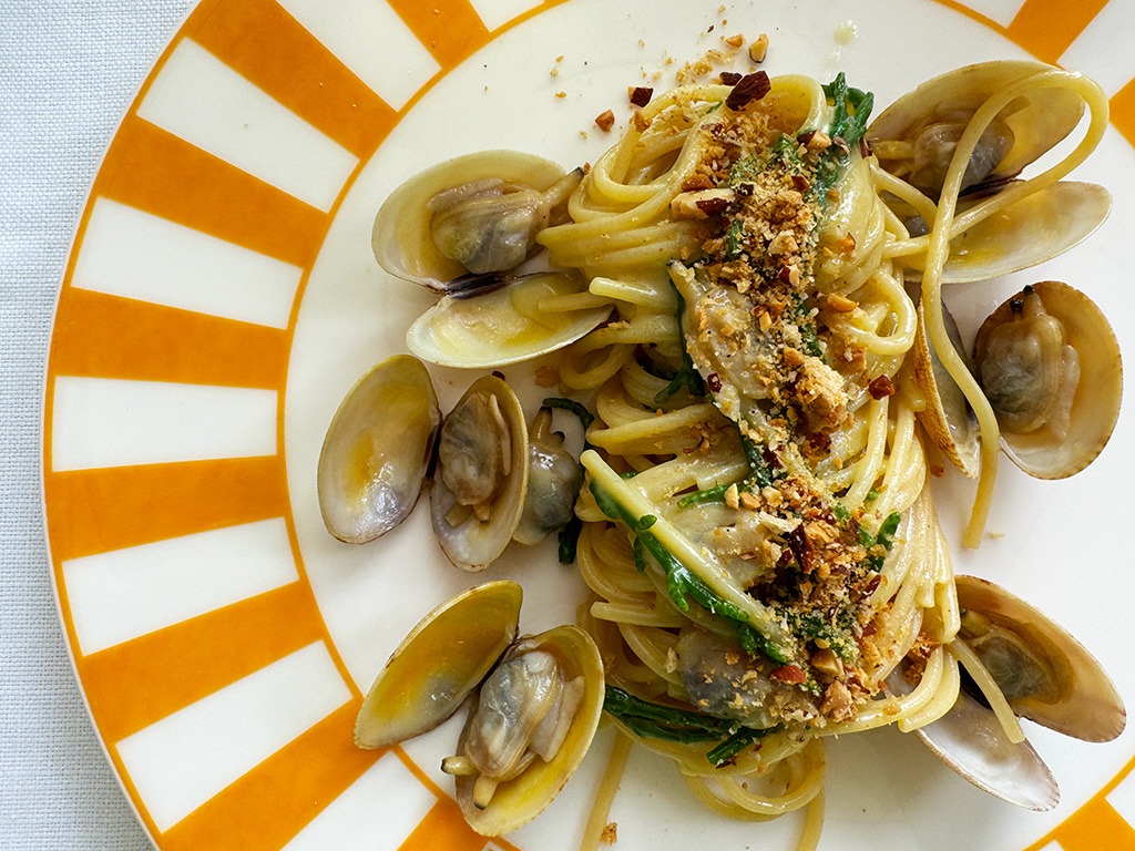 spaghetti alle vongole on yellow white striped plate in capri