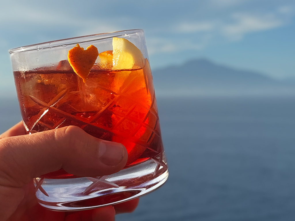 close up of negroni glass with heart shaped orange peel on it